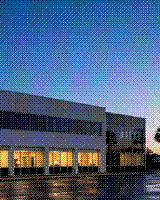 An office building at dusk, its lights on