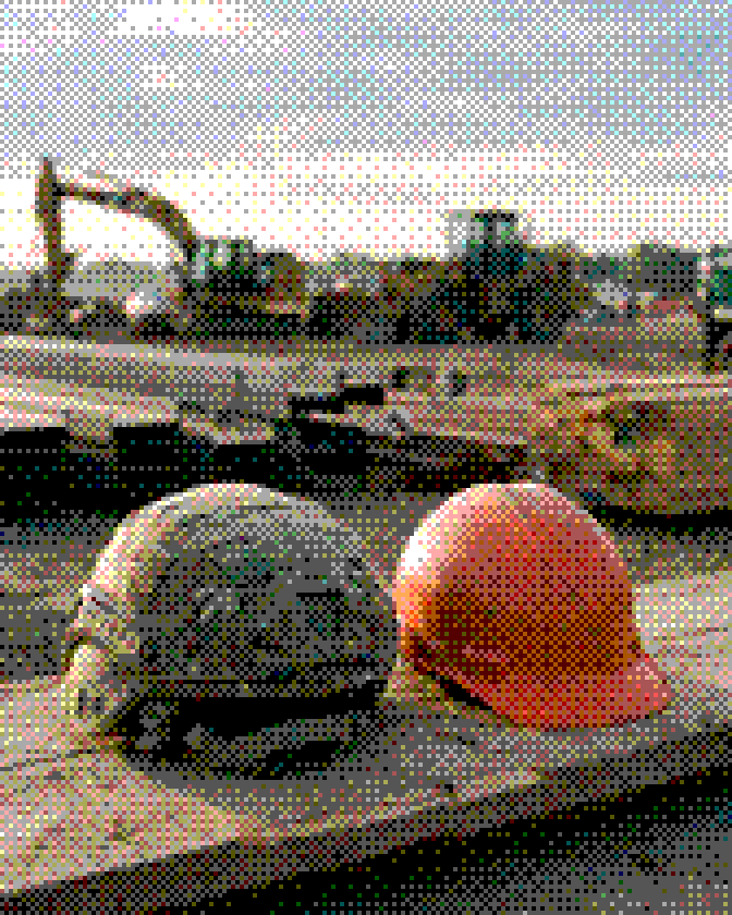 A combat helmet next to an orange hard hat on a stack of lumber at a job site